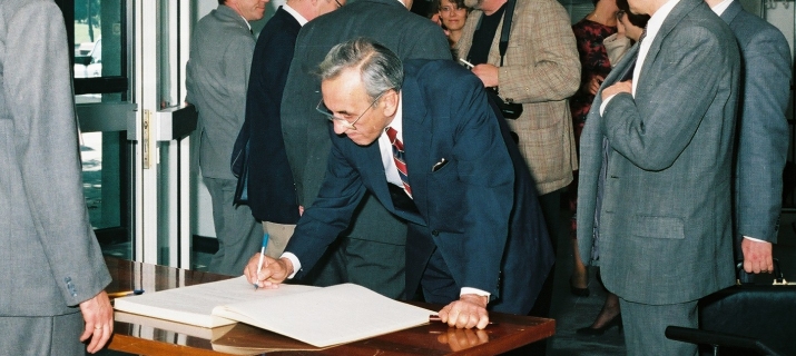 Na zdjęciu widać Tadeusza Mazowieckiego wpisującego się do księgi pamiątkowej.