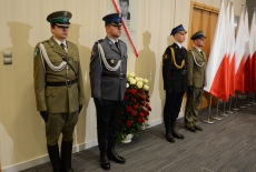 Przedstawiciele służb mundurowych pełnią wartę przy tablicy poświęconej śp. Władysławowi Stasiakowi. W tle flagi biało-czerwone.