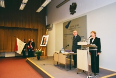 Dyrektor Maria Gintowt-Jankowicz stoi przy mównicy, Prof. Bartoszewski stoi przy stole prezydialnym