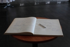 Księga honorowa KSAP leży otwarta na stoliku. Na niej leży długopis.