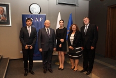Goście z zagranicy stoją z Dyrektorem Janem Pastwą w Auli KSAP na tle roll up KSAP i flag UE i Polski