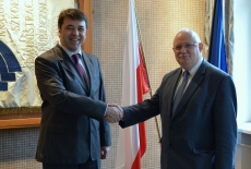 Dyrektor Pastwa podaje rękę uczestnikowi delegacji na tle sztandaru KSA oraz flag Polski i UE