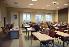 Eugeniusz Smolar siedzi i wygłasza wykład przed siedzącymi słuchaczami KSAP