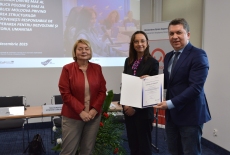 Uczestnik pozuje z dyplomem, obok pani z MSZ i dyrektor KSAP