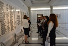 Uczestnicy seminarium stoją w Sejmie RP przed tablicą upamiętniającą poległych podczas II Wojny Światowej posłów i senatorów.