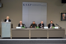 Przy mównicy stoi i przemawia przedstawicielka KSAP, przy stole prezydialnym siedzą przedstawiciele Iranu i polskiego MSZ.