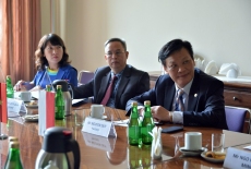 Trzech uczestników delegacji Wietnamu siedzi przy stole.