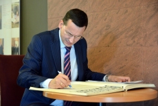 Minister Morawicki wpisuje się do księgi pamiątkowej.