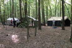Słuchacze KSAP stoją pomiędzy namiotami w lesie.