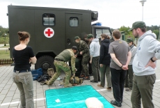 Słuchacze stoją przed samochodem wojskowym przeznaczonym do udzielania pierwszej pomocy