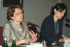 przy stole prezydialnym siedzą: Grażyna Kopińska która mówi do mikrofonu i Anna Jaroń