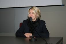 Anna Paszka siedząc przy stole mówi do mikrofonu.