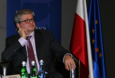 Paweł Soloch na tle baneru KSAP i flagi polskiej i Unii Europejskiej
