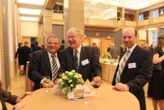 trzech mężczyzn stoi przy stole się śmieje