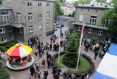 Zaproszeni goście na dziedzińcu KSAPobok stoi kolorowa karuzela dla dzieci