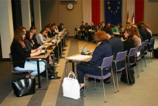 Widok na salę w której siedzą za stołami uczestnicy. Symulacja konferencji międzynarodowej.