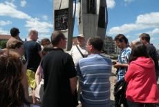Dyrekto Jan Pastwa i uczestnicy rejsu stoją pod pomnikiem poległych stoczniowców