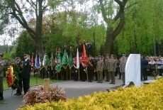 Żołnierze trzymają wieńce, a z tyłu stoją zgromadzeni żałobnicy