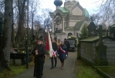 Poczet sztandarowy KSAP idzie za księdzem na cmentarzu. Za nimi jedzie trumna, a dalej idą pozostali goście ceremonii.