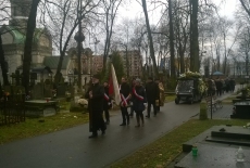 Poczet sztandarowy KSAP idzie za księdzem na cmentarzu. Za nimi jedzie trumna, a dalej idą pozostali goście ceremonii.