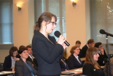 Uczestniczka wykładu stojąc pośrodku sali zadaje pytanie do mikrofonu.
