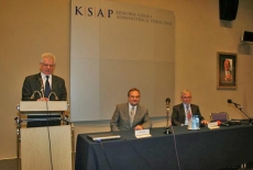 Dyrektor KSAP Jacek Czaputowicz przemawia na mównicy obok siedzi dwóch Panów współprowadzacych