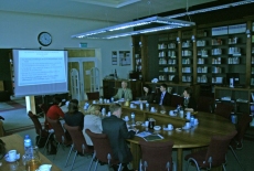 prof. Witold Mikułowski oraz goście spotkania siedzą przy stole w bibliotece KSAP