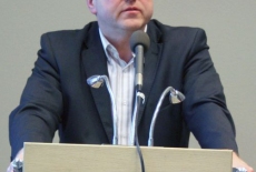Pan Grzegorz Górski stoi przy mównicy i przemawia