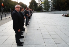 Dyrektor stoi przed pomnikiem z innymi uczestnikami.