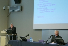 prof. Gaert Bouckaert stoi przy mównicy i przemawia, obok przy stole prezydialnym siedzi Dyrektor KSAP