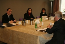 Uczestnicy spotkania siedzą przy stole i rozmawiają