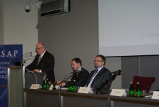 Dyrektor Jan Pastwa przemawia na mównicy, obok za stołem prezydialnym siedzą Wojciech Kalwat , Piotr Szlanta