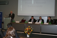 Dyrektor KSAP Jacek Czaputowicz przemawia na mównicy. Obok przy stole siedzą Sławomir Brodziński Mirosław Stec i Paweł Banaś