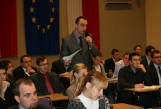 Uczestnik spotkania stoi i mówi do mikrofonu