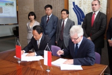 przedstawiciel delegacji Chin i Dyrektor KSAP siedza przy stole i podpisują dokumenty