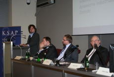 Pan Piotr Koryś przemawia na mównicy obok Za stołem prezydialnym siedzą Wojciech Kalwat , Piotr Szlanta, Jan Pastwa