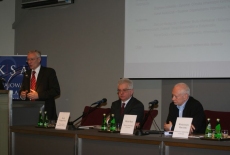 Pan stoi przy mównicy i przemawia obok siedzą Dyrektor KSAP i Michał Boni