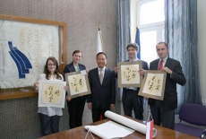Przedstawiciele KSAP spotkania stoją i trzymaja plakaty z chińskimi literami