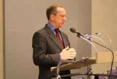 Pan Jan Tombiński stoi przy mównicy i przemawia