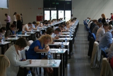 Sala egzaminacyjna, kandydaci siedzą przy stolikach i piszą egzamin