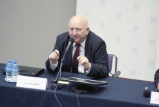 Józef Oleksy siedzi i mówi do mikrofonu