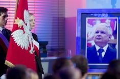Portret Prezydenta Lecha Kaczyńskiego stoi na sztaludze. Z lewej strony stoi poczet sztandarowy. Widoczny sztandar KSAP.
