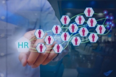 Grafika przedstawiająca dłoń osoby naciskającej ikonę z napisem ‘HR’, z której wychodzi sieć połączonych sześciokątnych ikon symbolizujących pracowników