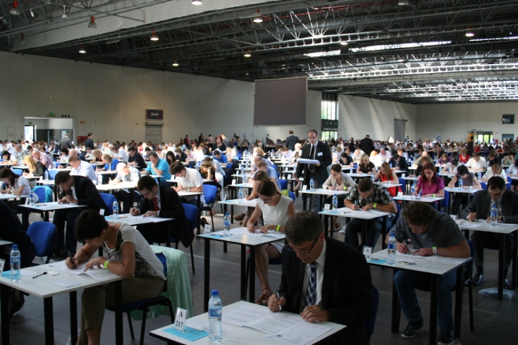 Na sali przy stolikach siedzą osoby zdające egzamin
