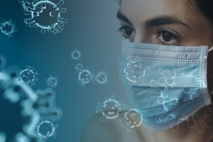 twarz kobiety w masce chirurgicznej, wokół latające cząsteczki wirusa