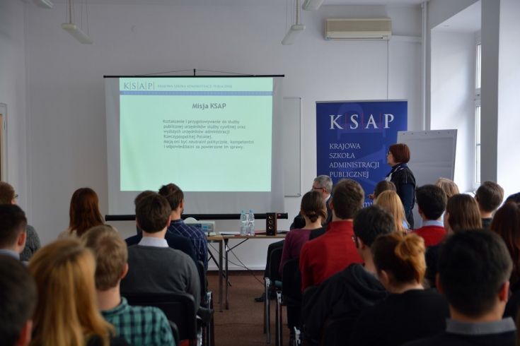 Uczestnicy spotkania w sali wykładowej KSAP. W tle baner KSAP oraz ekran z wyświetloną prezentacją na temat KSAP.