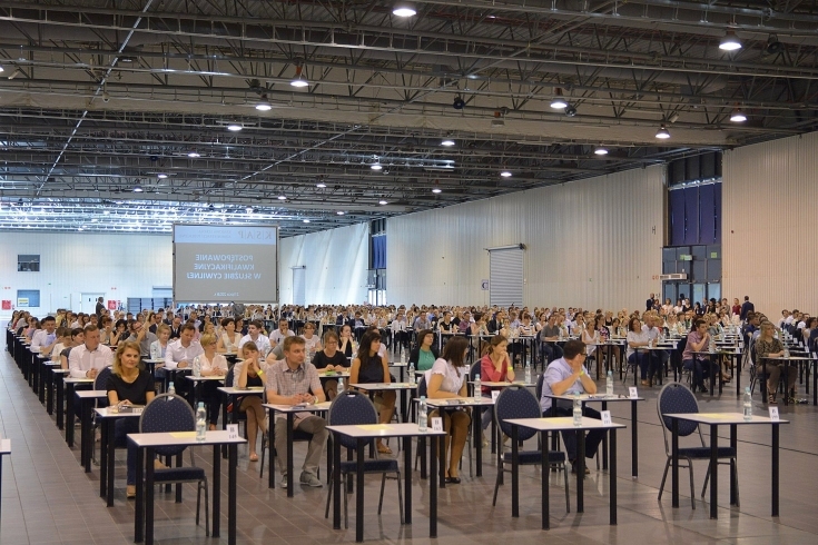 Uczestnicy na Hali EXPO siedzą przy pojedynczych stolikach i piszą test.