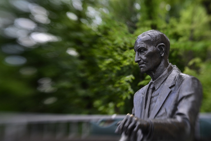 Pomnik Jana Karskiego przedstawiający jego popiersie na tle zieleni, za pomnikiem park
