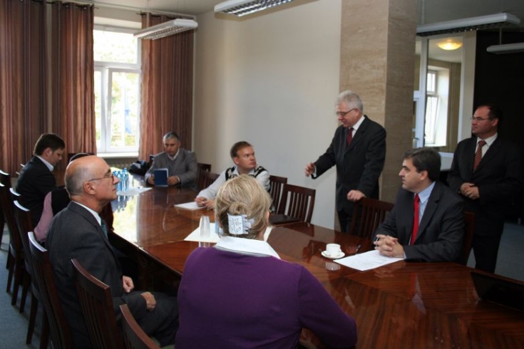  przedstawiciele Akademii Zarządzania Publicznego w Rotsowie siedza przy stole. Dyrektor KSAP stoi i mówi